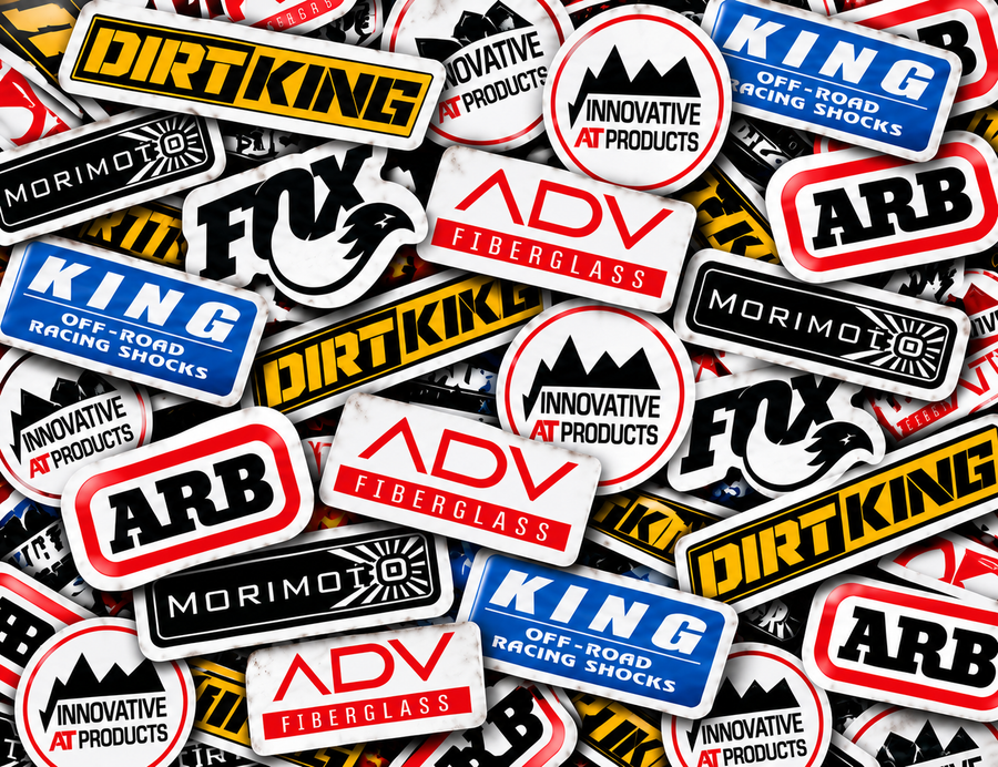 Off-road brand sticker collage featuring ADV Fiberglass, Innovative AT Products, Dirt King, ARB, Morimoto, FOX and King Shocks